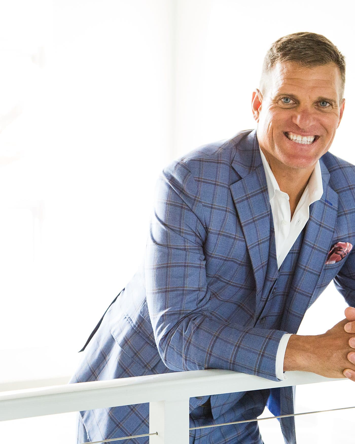 Dave VanHoose in a blue suit leaning on a railing, ready to welcome you in